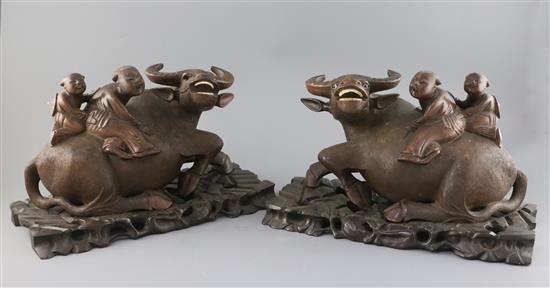 A pair of Chinese hardwood groups of children riding a buffalo, early 20th century, L. 37.5cm